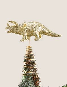 a gold alligator on top of a christmas tree with pine cones in the foreground