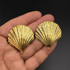 two gold seashells sitting on top of each other in someone's hand