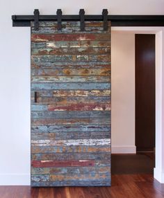 a wooden door with metal hardware on the top and bottom, in front of a white wall