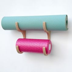 a wall mounted yoga mat and exercise roller on a white background with a pink handle