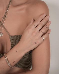 a woman with tattoos on her arm and chest wearing a bra top, bracelets and rings