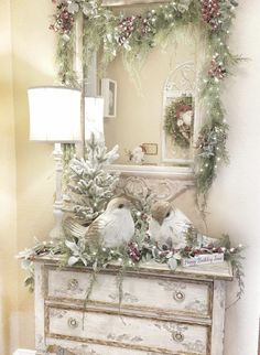 two birds sitting on top of a dresser next to a mirror and christmas wreaths