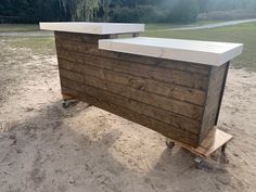 a wooden bar sitting on top of a sandy beach next to a forest in the background