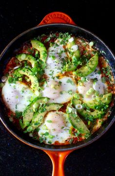 an omelet with eggs, avocado and cheese in a skillet