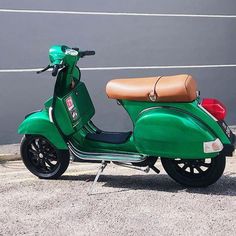 a green scooter is parked in front of a building with a brown leather seat