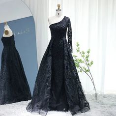 two black dresses are on display in front of a white backdrop and one has a mannequin