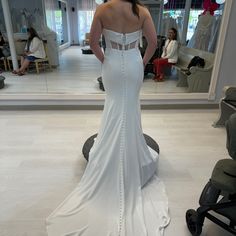 a woman in a white wedding dress looking at herself in the mirror with her back to the camera