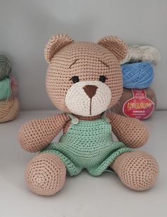 a crocheted teddy bear sitting next to some yarn