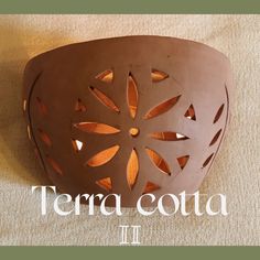 there is a vase that has cut out designs on it and the words terra cota ii above it