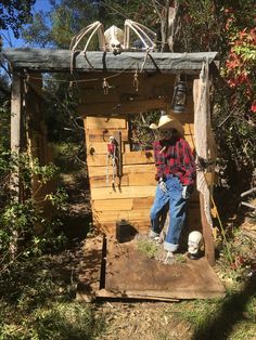 a man in cowboy hat standing next to a wooden structure with skeletons hanging from it