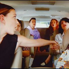 a group of people sitting in the back of a car with their hands on each other