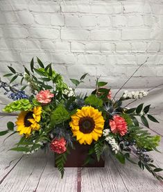 a vase filled with lots of flowers on top of a wooden table next to a brick wall