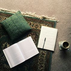 an open book, coffee cup and pen on a rug