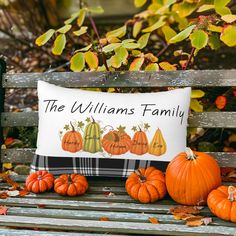 a family pillow with pumpkins and gourds sitting on a bench