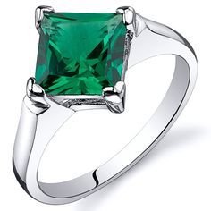 an emerald colored stone ring with two claws on the band, set in white gold