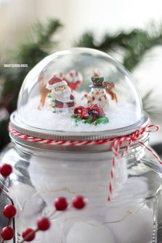 a glass jar filled with snowballs and santa clause figurines sitting on top of a table