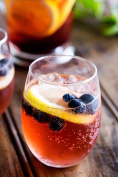 two glasses filled with drinks sitting on top of a wooden table