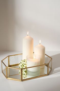 three white candles sitting on top of a glass tray