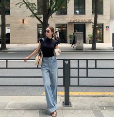 a woman standing next to a pole on the side of a road with her hand in her pocket