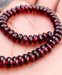 two red beads sitting on top of each other in someone's hand with their fingers