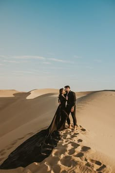 a man and woman standing in the sand dunes