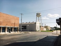 an empty street with buildings and a water tower in the background