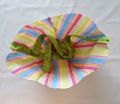 a paper plate with a green bow on it and some thread in the middle, sitting on a white table cloth