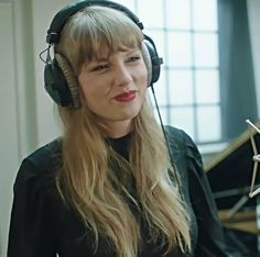 a woman wearing headphones standing in front of a piano