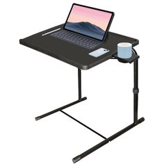 a laptop computer sitting on top of a black desk with a coffee cup next to it