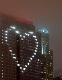 the city skyline is lit up at night, with skyscrapers in the foreground