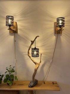 two wooden sculptures with lights on them are sitting on a table next to a potted plant