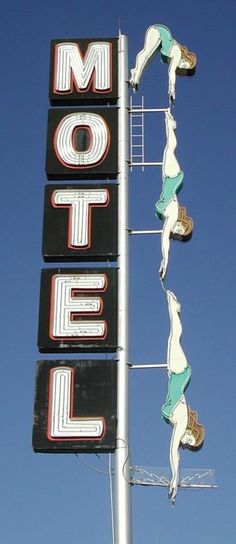 an old motel sign with people hanging from it