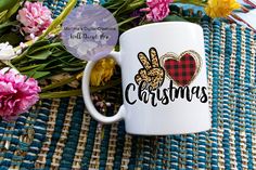 a white coffee mug sitting on top of a table next to flowers