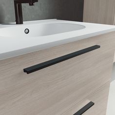 a white sink sitting next to a wooden cabinet with black handles on it's sides