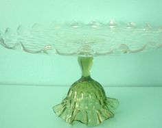 a green glass cake plate on a white tablecloth with a light blue wall in the background