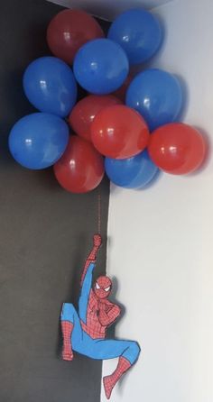 a spiderman balloon is suspended from the ceiling by some red, white and blue balloons