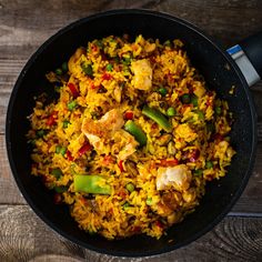 a pan filled with rice and vegetables on top of a wooden table