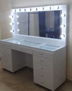 a white vanity with lighted mirror and drawers