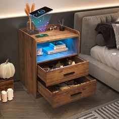 a night stand with two drawers and an electronic device on top, in front of a couch