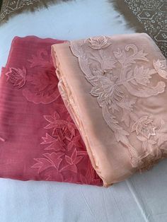 two pieces of pink and beige fabric on a bed