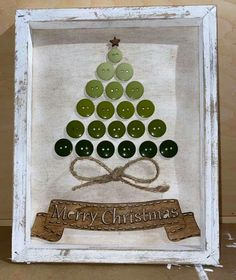 a christmas tree made out of buttons in a white frame with a ribbon around it