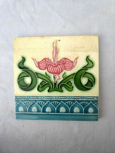 a ceramic tile with the word love written in green, pink and blue on it