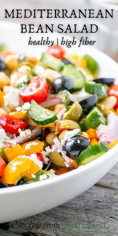 a white bowl filled with colorful vegetables on top of a wooden table