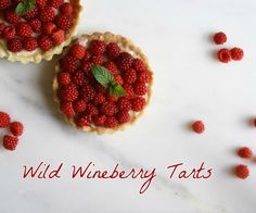 two raspberry tarts sitting on top of a white counter next to each other