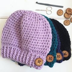 three crocheted beanies with buttons on them next to some scissors and other crafting supplies