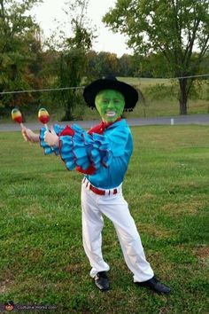 a man in costume is holding an apple and hitting it with his bat while standing on the grass