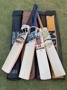 several cricket bats are laying on the grass in a bag with other items inside it