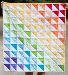 a person holding up a colorful quilt