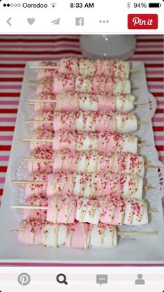 marshmallows and sprinkles are arranged on skewers on a plate