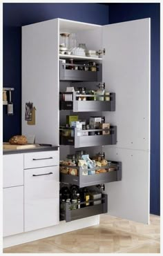 a kitchen with blue walls and white cupboards filled with food, drinks and other items